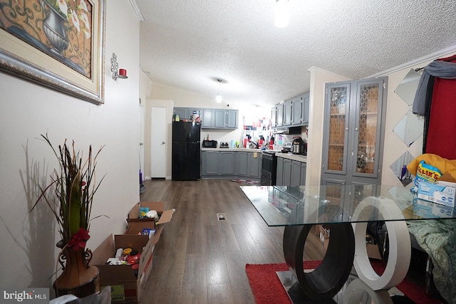 kitchen featuring dark wood-style floors, freestanding refrigerator, stainless steel electric stove, vaulted ceiling, and gray cabinetry