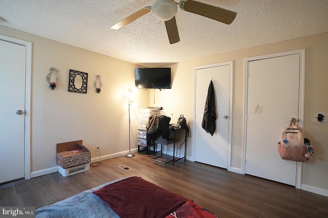 interior space featuring dark wood-style flooring, ceiling fan, a textured ceiling, and baseboards