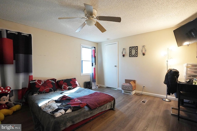 bedroom featuring ceiling fan, a textured ceiling, baseboards, and wood finished floors