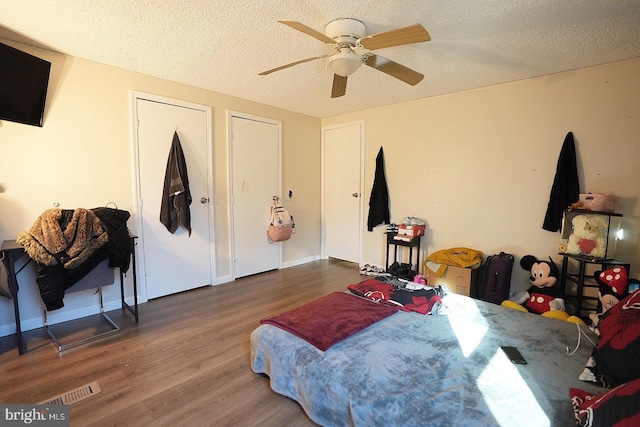 bedroom with a textured ceiling, ceiling fan, dark wood finished floors, and visible vents