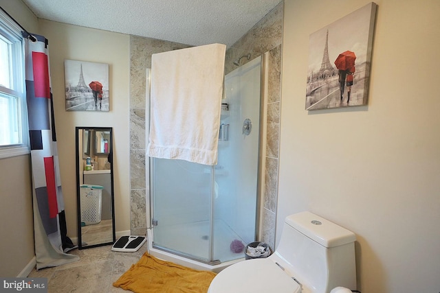 bathroom with toilet, a stall shower, and a textured ceiling