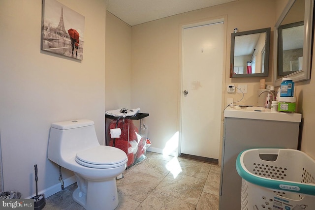 bathroom featuring toilet, baseboards, and vanity