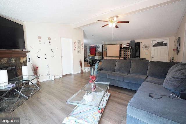 living room with a fireplace, lofted ceiling with beams, ceiling fan, wood finished floors, and baseboards