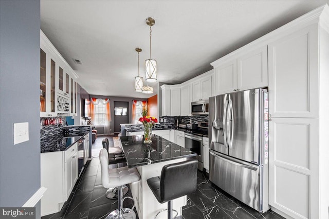 kitchen featuring a breakfast bar, stainless steel appliances, backsplash, glass insert cabinets, and white cabinets