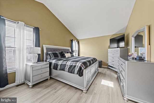 bedroom featuring light wood-style floors, lofted ceiling, and baseboards