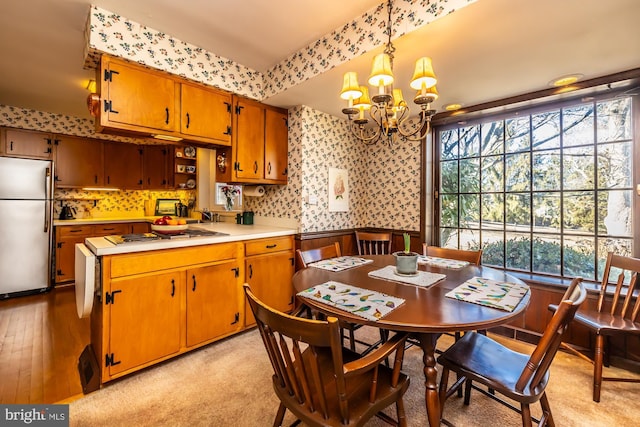 dining space with a chandelier, wainscoting, light wood-style flooring, and wallpapered walls