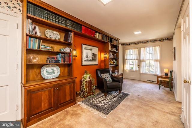 living area featuring baseboards and light colored carpet