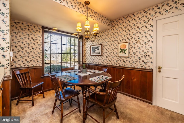 dining room featuring light carpet, a wainscoted wall, a chandelier, and wallpapered walls