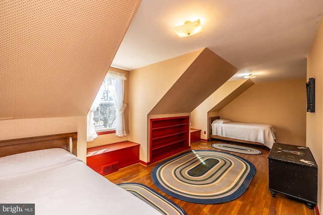 bedroom with lofted ceiling, visible vents, and wood finished floors