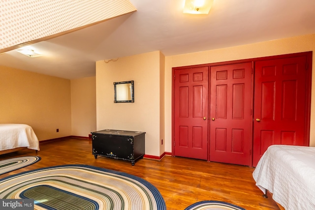 bedroom with a closet, wood finished floors, and baseboards