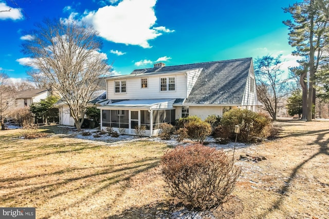 back of house with a sunroom, a shingled roof, and a lawn