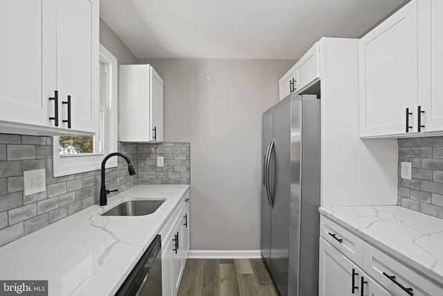 kitchen with stainless steel refrigerator with ice dispenser, a sink, white cabinets, and light stone countertops