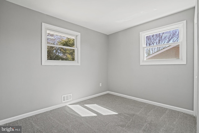 carpeted spare room featuring visible vents and baseboards