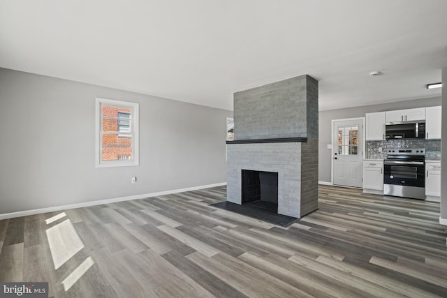 unfurnished living room with a fireplace, baseboards, and wood finished floors