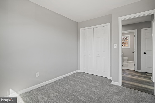 unfurnished bedroom featuring baseboards, dark carpet, and a closet