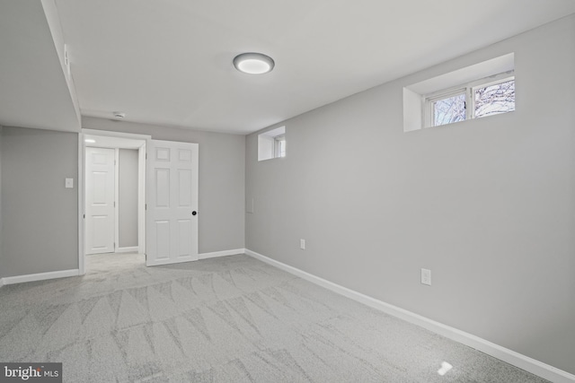 basement featuring light carpet, plenty of natural light, and baseboards