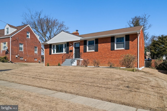 view of front facade with a chimney, a front lawn, and brick siding