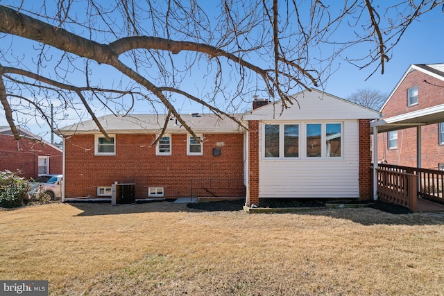 rear view of property featuring central AC, brick siding, and a lawn