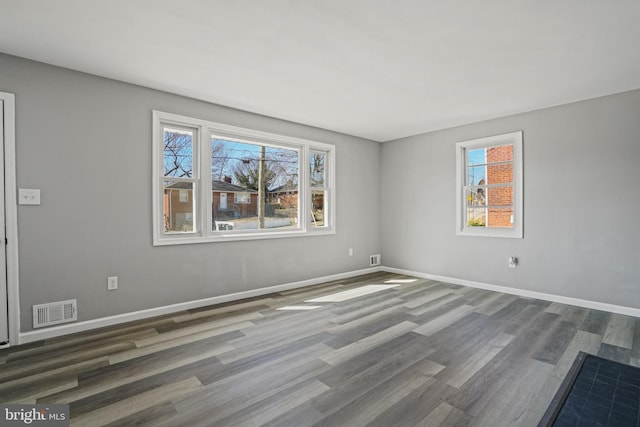 empty room featuring visible vents, baseboards, and wood finished floors