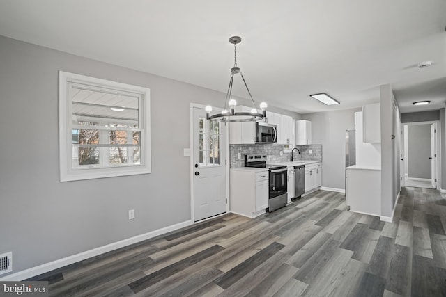 kitchen with a sink, white cabinets, light countertops, appliances with stainless steel finishes, and pendant lighting