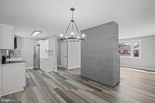 kitchen with white cabinetry, pendant lighting, a sink, and freestanding refrigerator