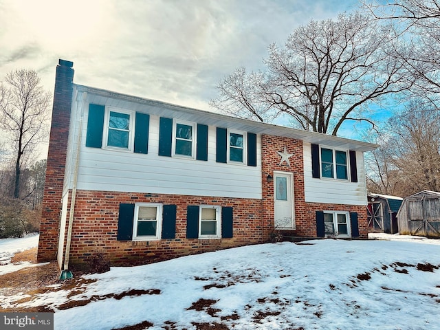 split foyer home featuring a storage shed and brick siding