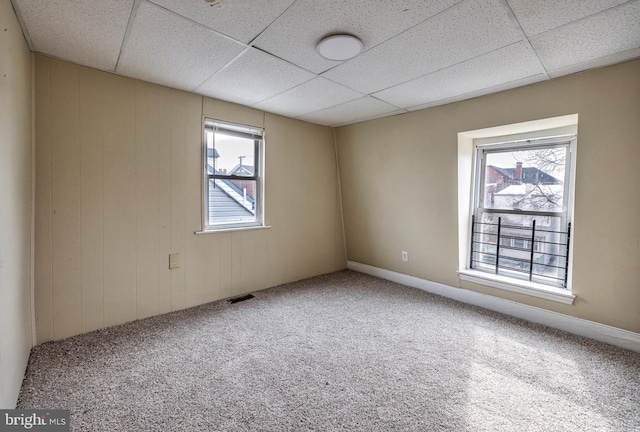 carpeted spare room with visible vents and a drop ceiling