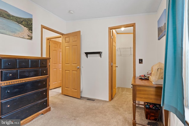 bedroom with light carpet, a spacious closet, and crown molding