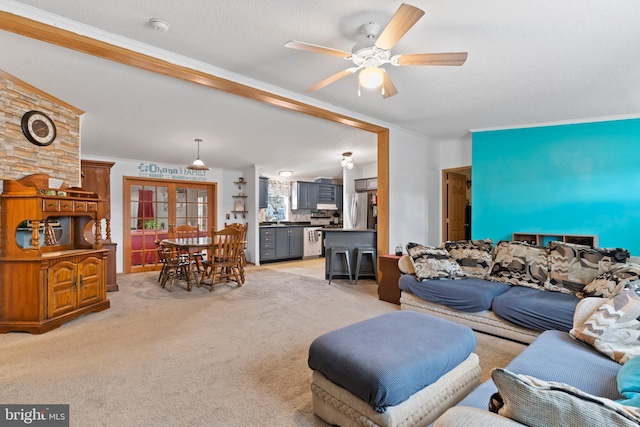 living area featuring french doors, light carpet, ceiling fan, and a textured ceiling