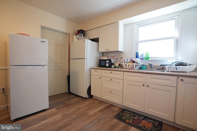 kitchen featuring light wood finished floors, light countertops, freestanding refrigerator, white cabinetry, and a sink