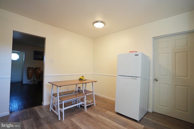 kitchen featuring baseboards, wood finished floors, and freestanding refrigerator