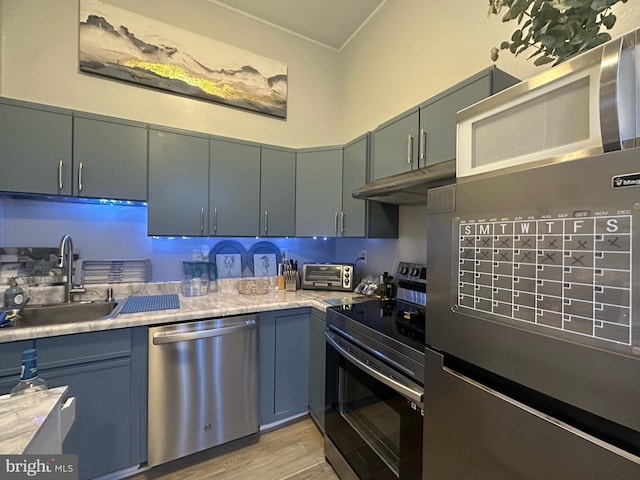 kitchen featuring a toaster, stainless steel appliances, light countertops, under cabinet range hood, and a sink