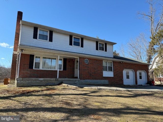 view of front of home featuring brick siding, a chimney, and a front lawn