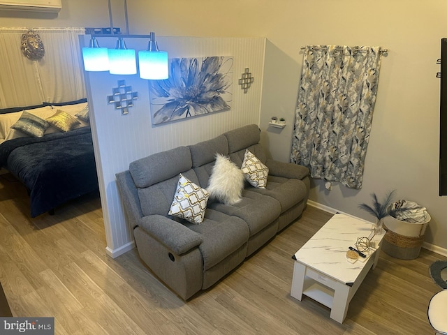 living room featuring baseboards, wood finished floors, and an AC wall unit