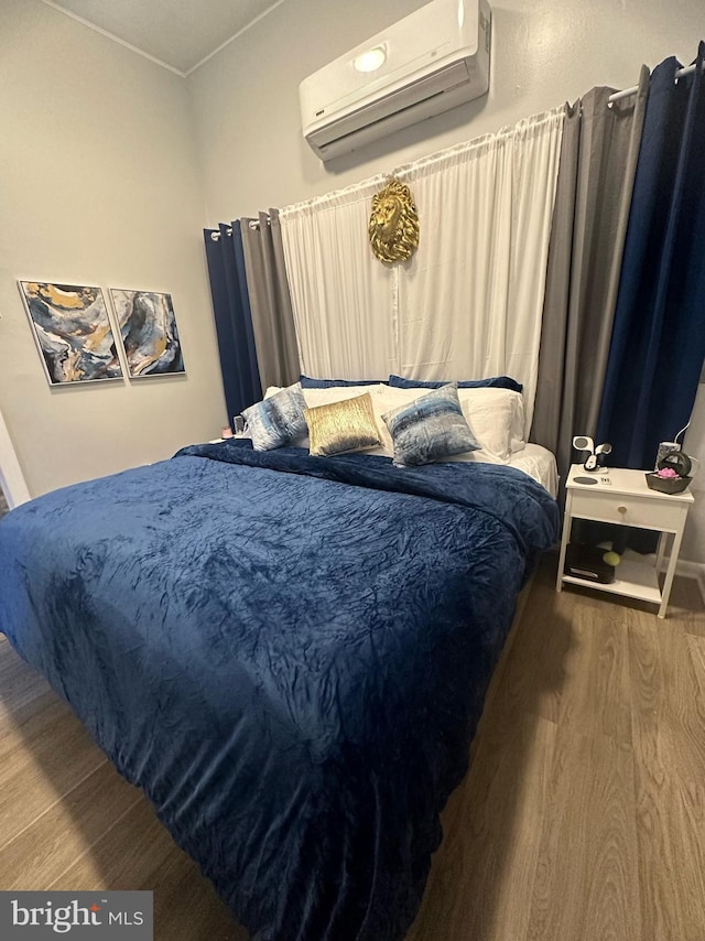 bedroom featuring a wall unit AC and wood finished floors