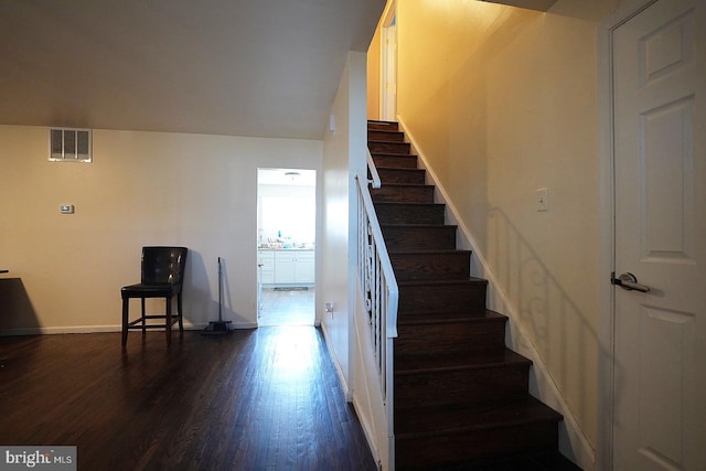 staircase featuring visible vents, baseboards, and wood finished floors