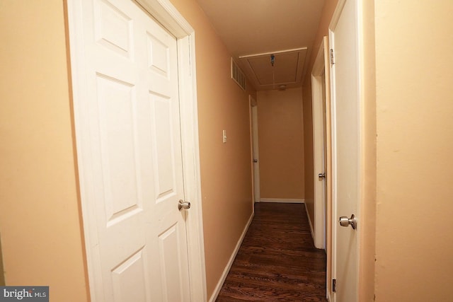 hallway with attic access, visible vents, dark wood finished floors, and baseboards