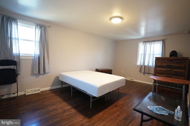 bedroom with dark wood-style floors, baseboards, and visible vents