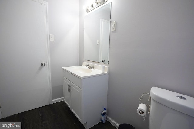 half bath featuring vanity, toilet, and wood finished floors