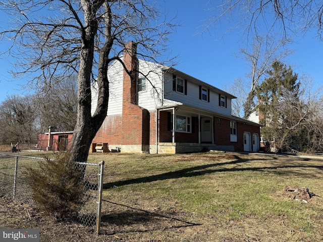 view of front of property with brick siding, a front lawn, a chimney, and fence