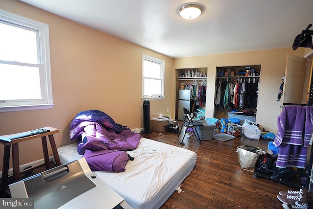 bedroom featuring a closet, dark wood-style flooring, and freestanding refrigerator