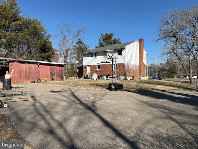 exterior space with a chimney, basketball court, and brick siding