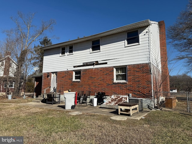 back of property featuring brick siding, a lawn, central AC, and a patio