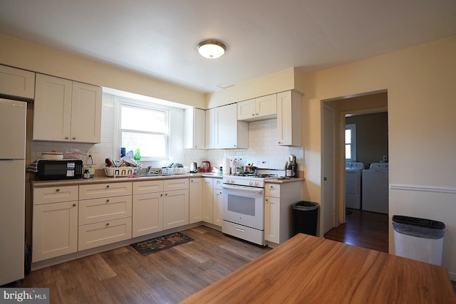 kitchen featuring white cabinets, white gas range oven, washer and clothes dryer, and freestanding refrigerator