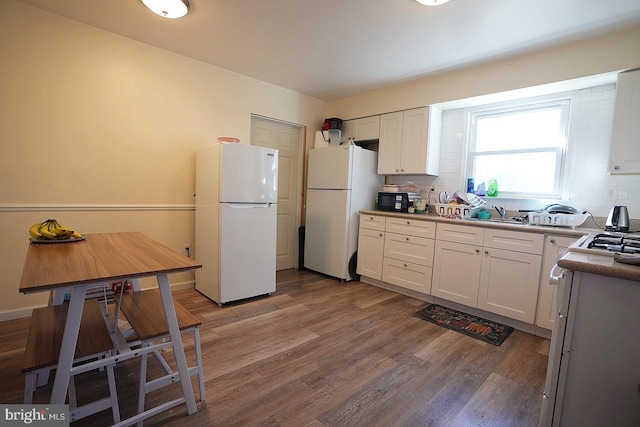 kitchen featuring tasteful backsplash, freestanding refrigerator, white cabinetry, and wood finished floors