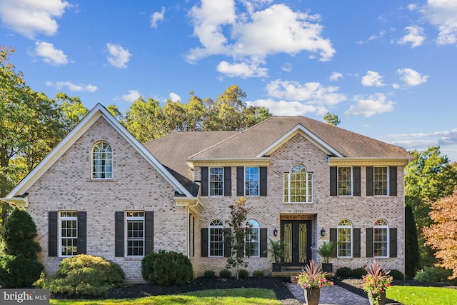 view of front of house with a front lawn, french doors, and brick siding