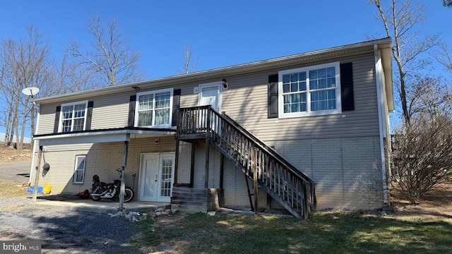 view of front of property featuring french doors, brick siding, and stairway
