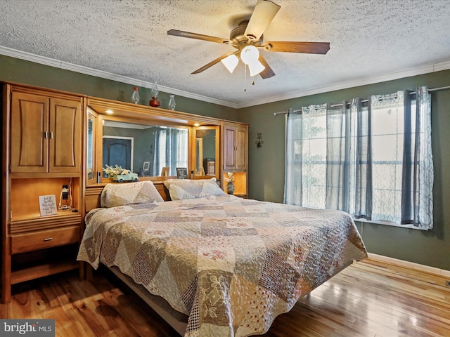 bedroom with crown molding, ceiling fan, a textured ceiling, wood finished floors, and baseboards