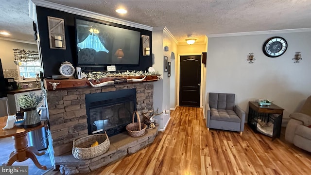 living area featuring a textured ceiling, ornamental molding, a fireplace, and wood finished floors