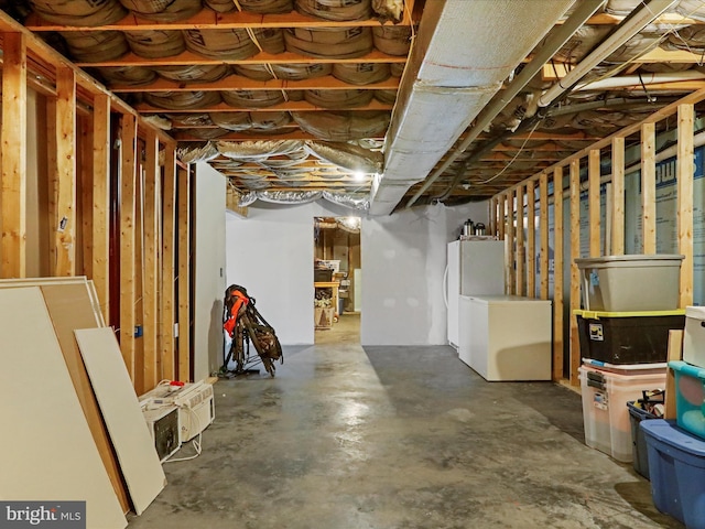 unfinished basement featuring fridge and freestanding refrigerator